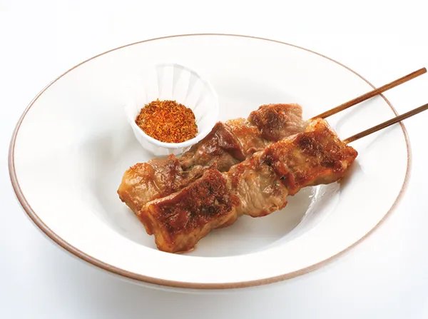 皿にのったラム肉の串焼きと、添えられたスパイスのアロスティチーニ